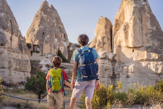 Father and son tourists on background of Unique geological formations in Love Valley in Cappadocia, popular travel destination in Turkey. Traveling with children in Turkey concept.