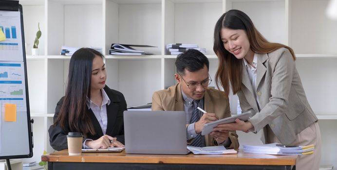 Group of young asian business people in smart casual wear working together in creative office using laptop...