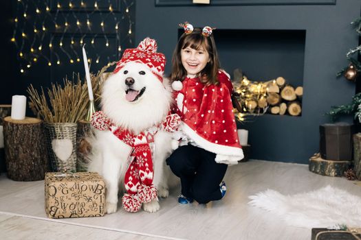 Happy woman owner and white Samoyed dog in winter day. Little girl and dog for Christmas smiling and looking at camera.