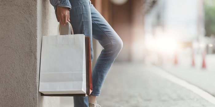 Asian fashionable woman walking at shopping mall with shopping bags while flash sale promotion.