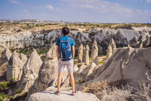Young man exploring valley with rock formations and fairy caves near Goreme in Cappadocia Turkey.