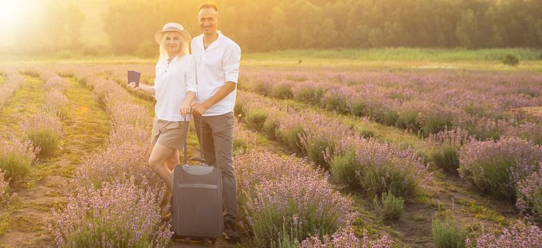 man and woman with travel suitcase in lavender field