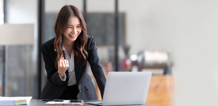 Beautiful asian woman using laptop computer, exciting and celebrating with good news of business successful. Small business startup concept...