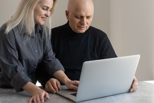 Happy smiling young girl teaching and showing new computer technology to her grandfather