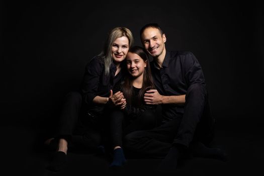 happy family mother, father, daughter on a black background.