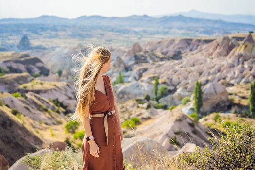 Young woman exploring valley with rock formations and fairy caves near Goreme in Cappadocia Turkey.