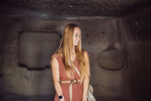 Young woman exploring valley with rock formations and fairy caves near Goreme in Cappadocia Turkey.