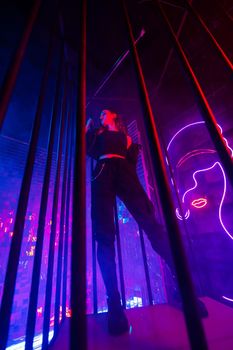 Caucasian woman in neon studio behind steel bars