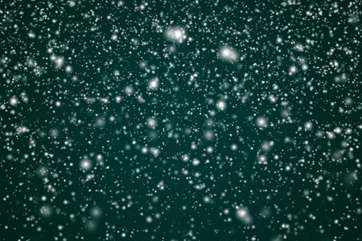 Winter holidays and wintertime background, white snow falling on festive green backdrop, snowflakes bokeh and snowfall particles as abstract snowing scene for Christmas and snowy holiday design. High quality 4k footage