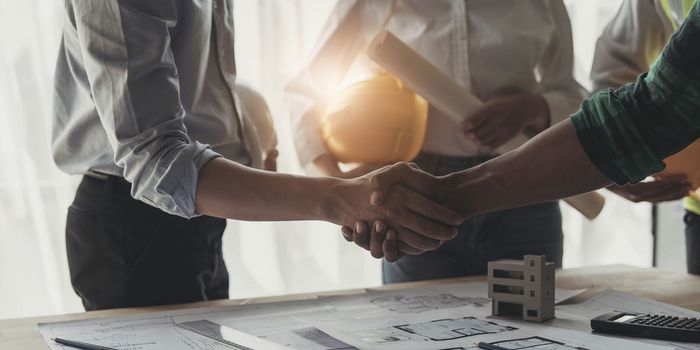 Professional Asian male engineer shaking hands with male architect after the meeting..