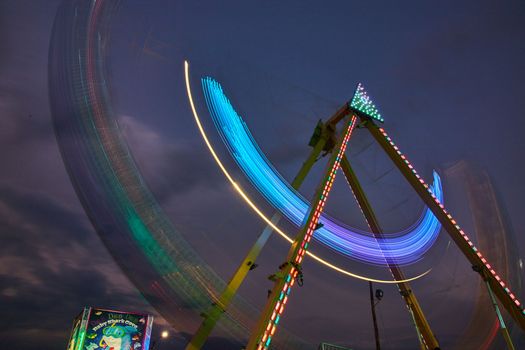 Image of Dusk carnival ride swinging with blurred lights at county fair