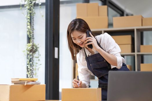 Young Asian Woman Working at home, Young Owner Woman talking to customer and working with happy emotion. People with online shopping SME entrepreneur or freelance working concept...