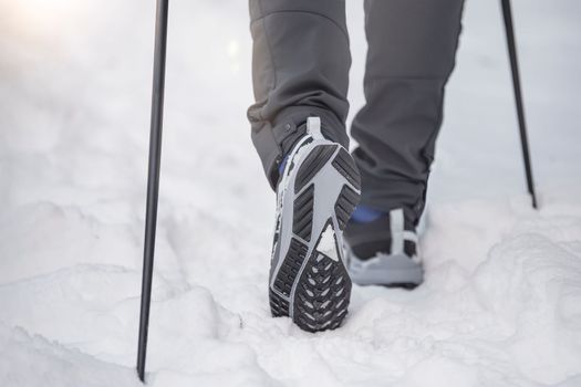 Nordic walking in winter. Sports activities in the winter on the snow. A man is engaged in Nordic walking with special sticks in the winter nature outdoors. Place for copy space