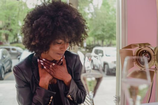 Young attractive African woman with happy cheerful smile drinking and having fun in a bar