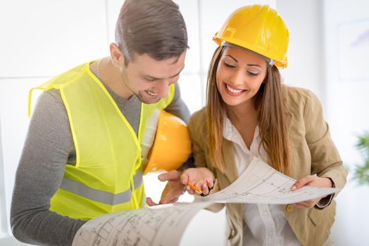 Two successful young architects discussing construction plans and planning what to change to be better. They are in the office.