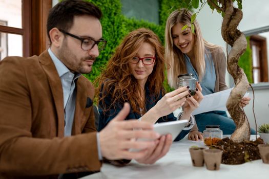 University colleague biologists taking experiment on sprout and checking the analysis of the sample of plant on the digital tablet.