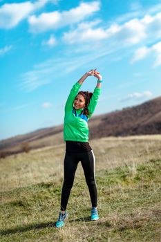 Young fitness woman doing stretching exercise after jogging in the nature.