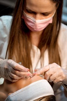 Beautician applying japanese method of drawing on eyebrows to model.  