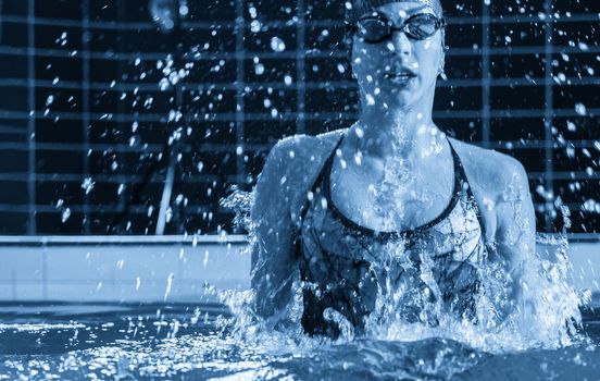 Young professional swimmer swims in an indoor pool with much splashing