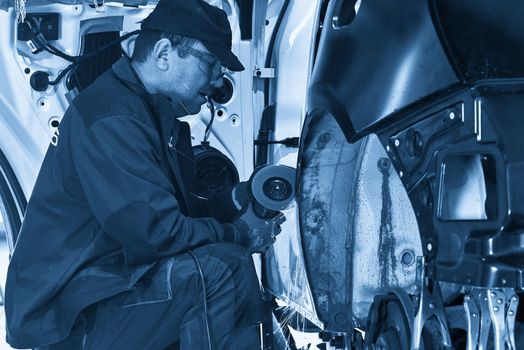 Cutting metal part with sparks in car service station