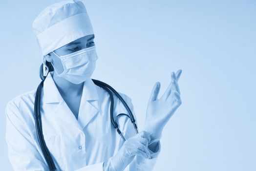 Close up of a female doctor putting latex gloves on a white background