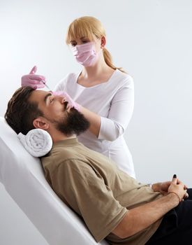 Closeup of bearded man getting beauty injection at aesthetic clinic. Doctor injecting anti-aging filler in handsome male face. Male cosmetology, aesthetic medicine concept