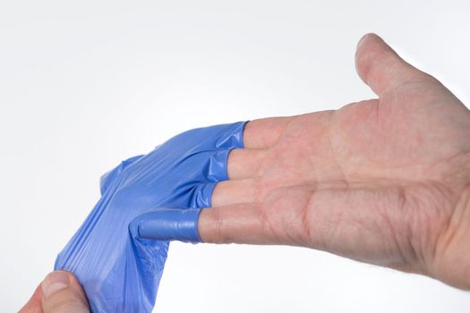 The doctor takes off his blue rubber gloves, the skin on his hands is wrinkled from moisture. Wrinkled fingers after wearing rubber gloves for a long time