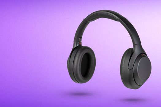 Headphones on a purple background. Wireless headphones in black, high quality, for advertising or product catalog