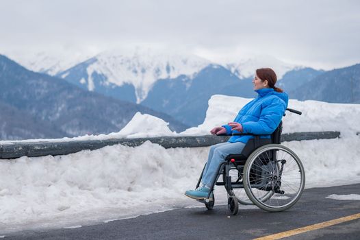 Caucasian woman in a wheelchair travels in the mountains in winter