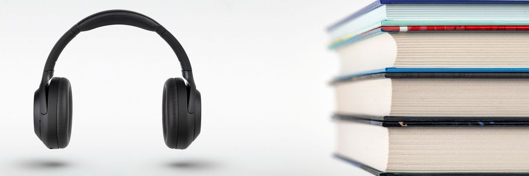 Audiobooks. Stack of books and headphones with space for copy space. Choice between books and audiobooks