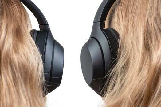 Woman in headphones isolated on white. Black headphones on a woman's head. Head of a fair-haired woman in headphones, rear view close-up