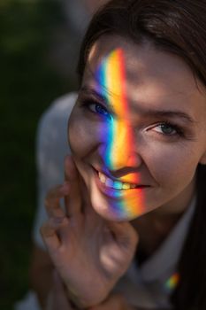 Portrait of caucasian woman with rainbow beam on her face outdoors