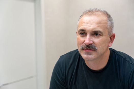 Middle-aged handsome man looking in mirror in a bathroom after shaving