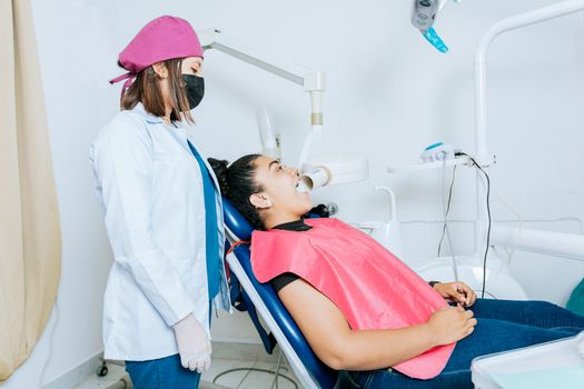 Intraoral radiography concept. Dentist doing intraoral dental x-ray to patient, Side view of dentist doing x-ray to female patient, female dentist doing dental x-ray in office