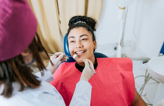 Close up of female dentist doing dental checkup to smiling patient, Patient lying on chair smiling at dentist, Dentist doing dental checkup to female patien