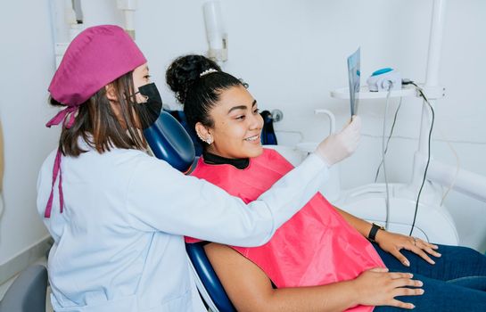 Dentist showing patient x-ray, Dentist with patient reviewing the x-ray. Patient looking at x-ray with dentist, Concept of dentist showing x-ray examination to female patient