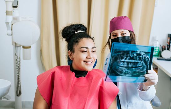 Dentist with patient reviewing the x-ray. Patient looking at x-ray with dentist, Concept of dentist showing x-ray examination to female patient, Dentist showing patient x-ray