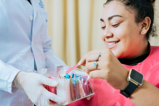 Dental patient choosing dental braces, Patient with dentist choosing colored rubber band. Patient with dentist choosing dental braces