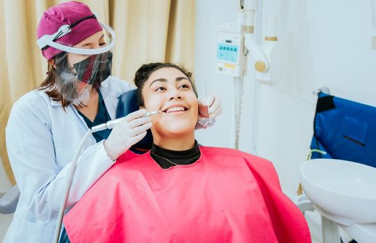 Female dentist cleaning a patient mouth with a drill. Close-up of a stomatologist cleaning a woman teeth, Stomatologist cleaning caries with drill, Stomatologist cleaning a patient teeth