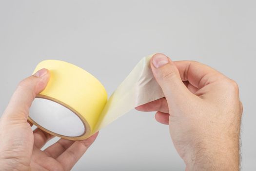 Paper adhesive tape isolated on white. A roll of paper duct tape in the hands of a white man. Unfolded adhesive tape with space for text