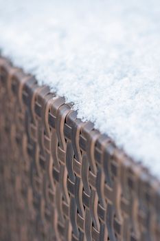 Care and storage of garden furniture in winter. texture of street furniture in winter. Artificial rattan covered with snow close-up