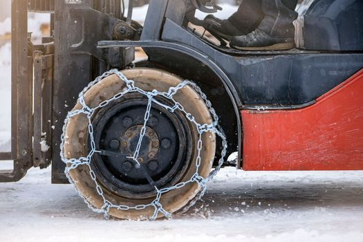 Tractor wheel with chain. Tractor or loader on a slippery snowy road. Loaders drive on snow with anti-skid chains