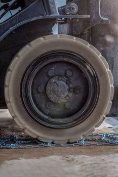 The process of installing an anti-skid chain on a wheel in winter. Preparing a loader, tractor or truck for a snowy road. Snow chains close up.