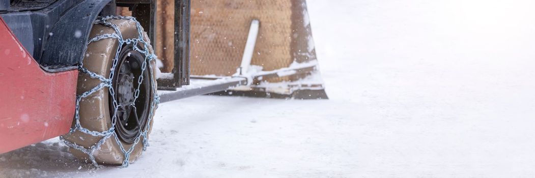 Tractor wheel with chain. Tractor or loader on a slippery snowy road. Loaders drive on snow with anti-skid chains