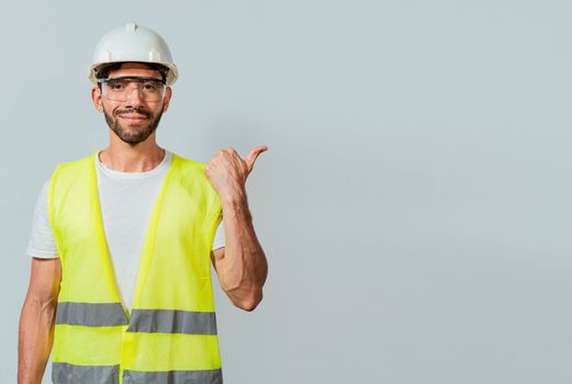 Portrait of engineer man pointing aside. Construction worker with vest pointing at an advertisement. Engineer man pointing to side. Builder engineer pointing finger to the right isolated