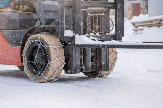 Tractor wheel with chain. Tractor or loader on a slippery snowy road. Loaders drive on snow with anti-skid chains