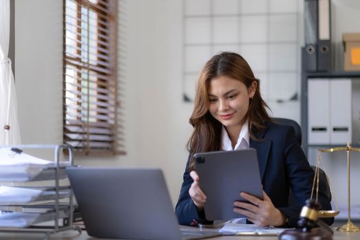 Attractive young lawyer in office Business woman and lawyers discussing contract papers with brass scale on wooden desk in office. Law, legal services, advice, Justice and real estate concept...