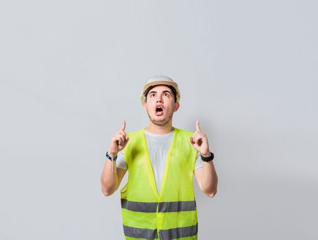 Amazed engineer pointing at an advertisement. Concept of an engineer with astonished face pointing at blank space, Amazed engineer man pointing up, Surprised young architect pointing up
