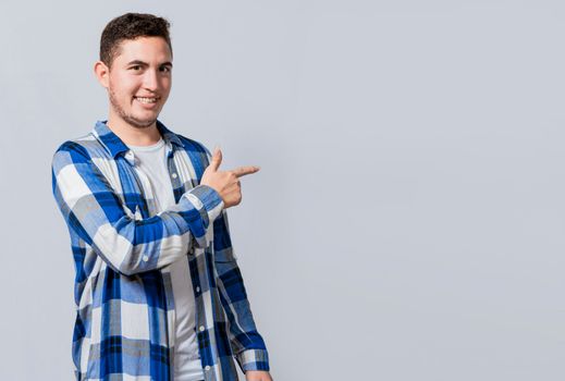 Smiling handsome man recommending something with his fingers. Caucasian handsome guy pointing his finger at a blank space, Smiling teenager pointing fingers to the side