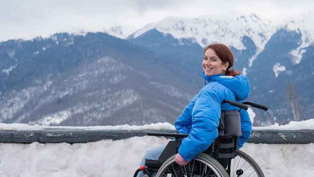 Caucasian woman in a wheelchair travels in the mountains in winter